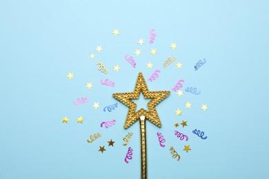 Photo of Beautiful golden magic wand and confetti on light blue background, flat lay