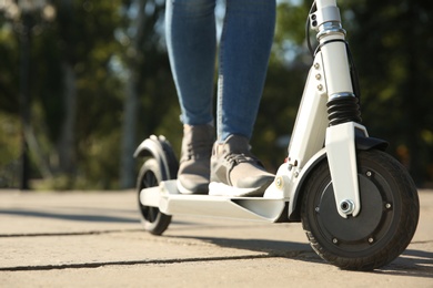 Photo of Woman riding electric kick scooter outdoors, closeup