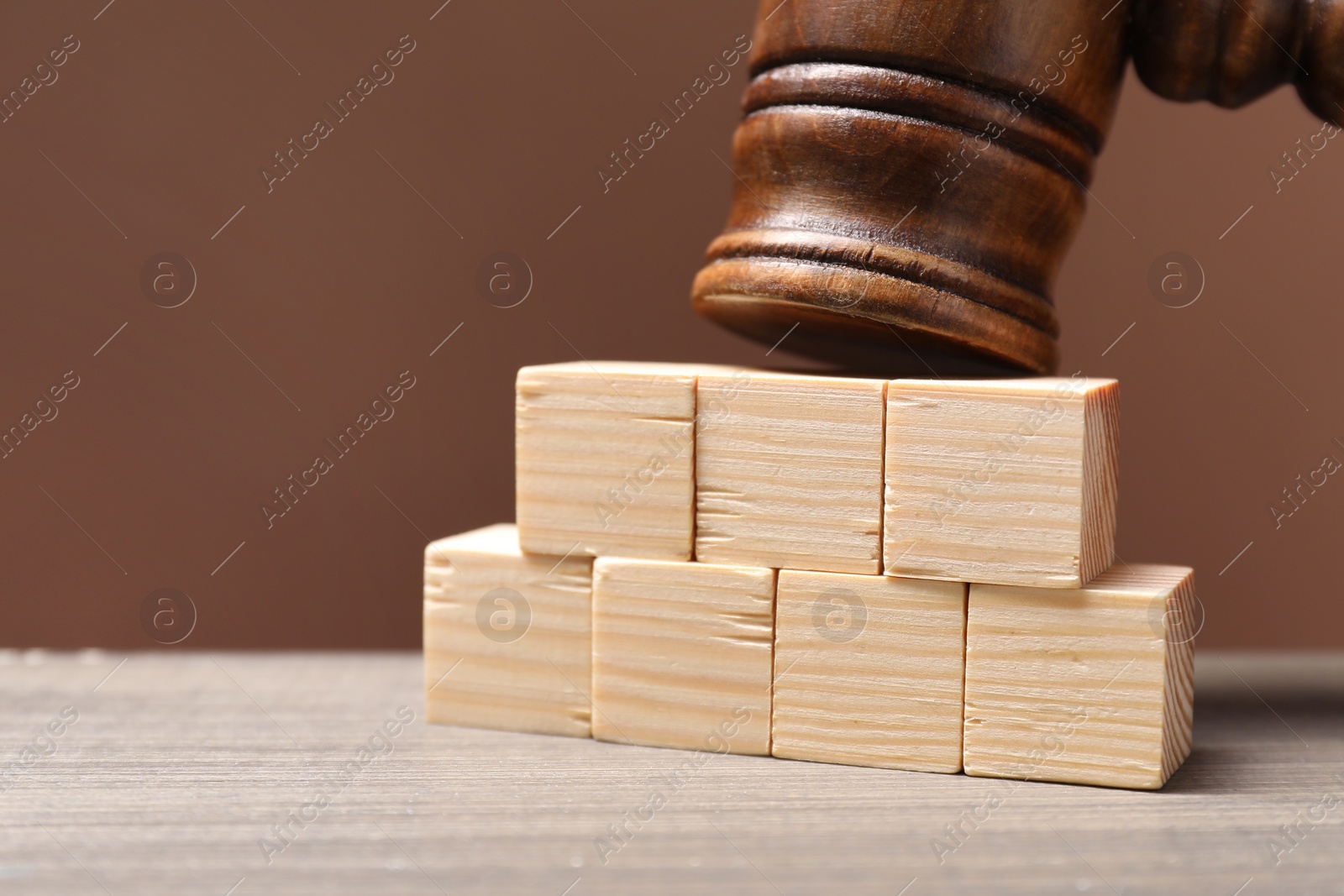 Photo of Law. Blank cubes and gavel on wooden table against brown background, closeup. Space for text