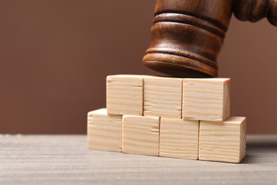 Photo of Law. Blank cubes and gavel on wooden table against brown background, closeup. Space for text