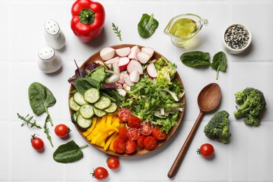 Vegetarian diet. Plate with tasty vegetables and spoon at white tiled table, flat lay