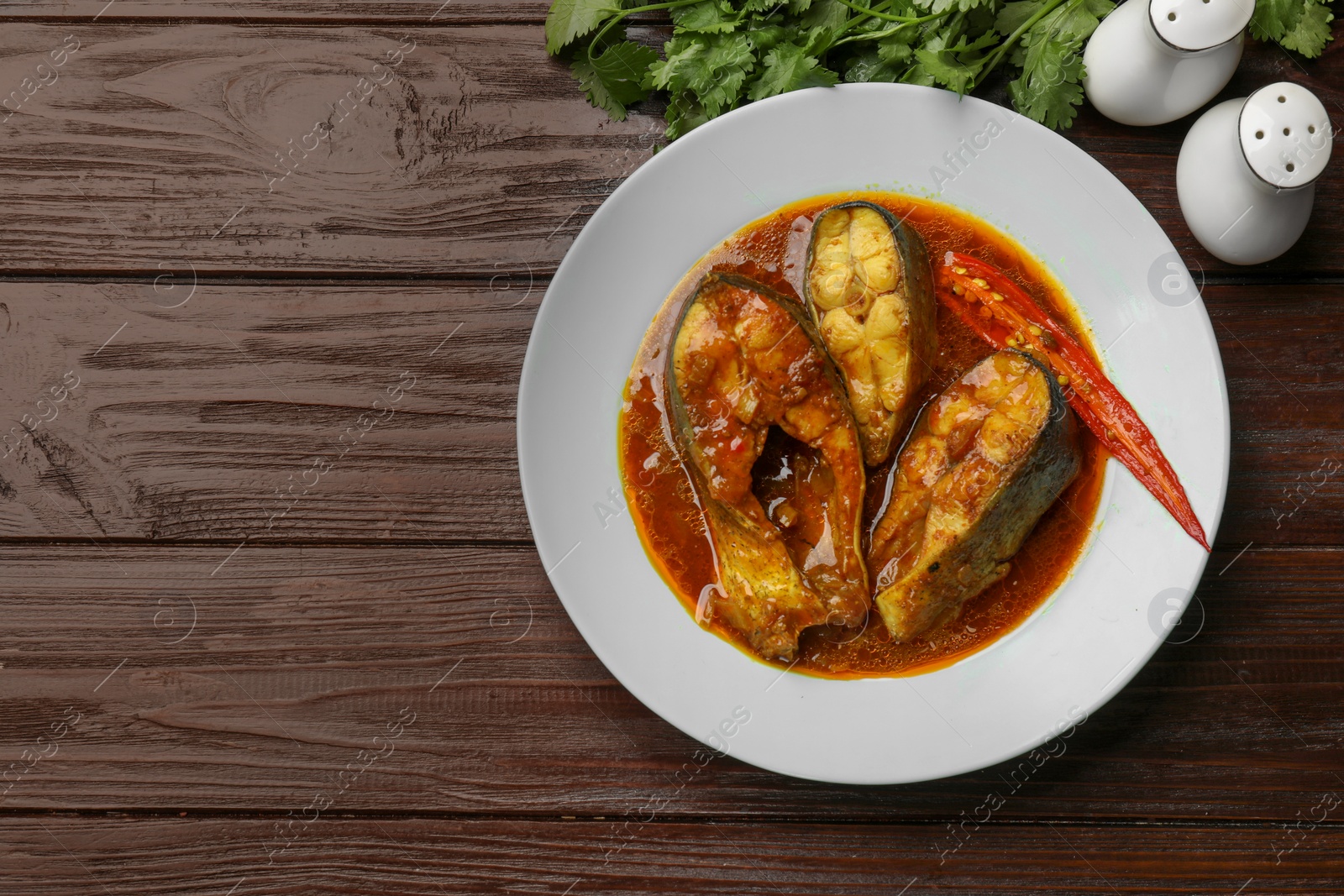 Photo of Tasty fish curry served on wooden table, flat lay. Space for text. Indian cuisine