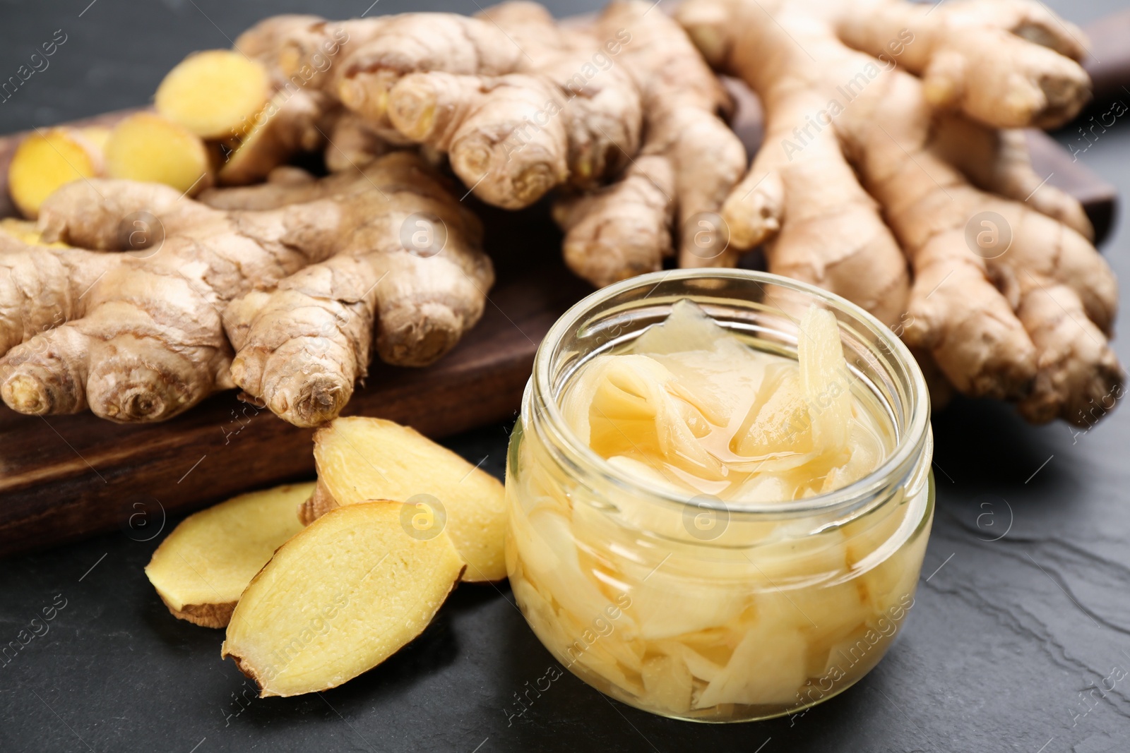 Photo of Spicy pickled ginger and root on black table