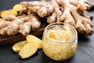 Photo of Spicy pickled ginger and root on black table