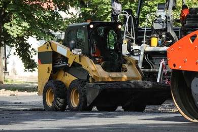 Photo of Modern skid loader on city street. Road repair service