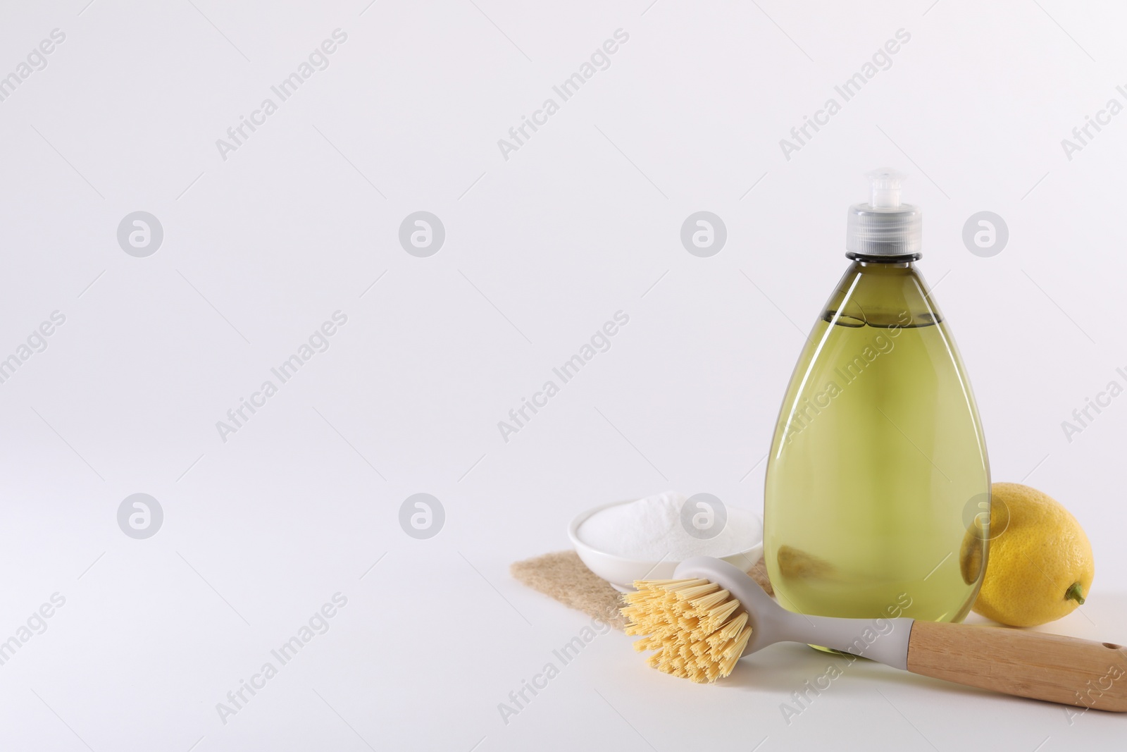 Photo of Bottles of cleaning product, brush, baking soda and lemon on white background