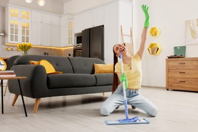 Photo of Spring cleaning. Young woman with mop singing while tidying up at home