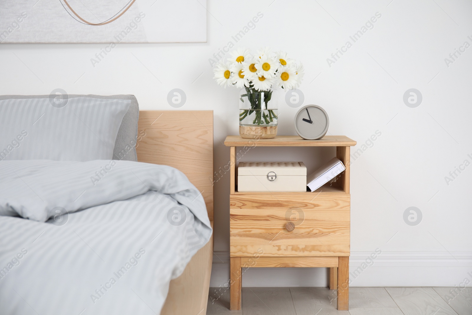 Photo of Bouquet of beautiful daisy flowers on wooden nightstand in bedroom