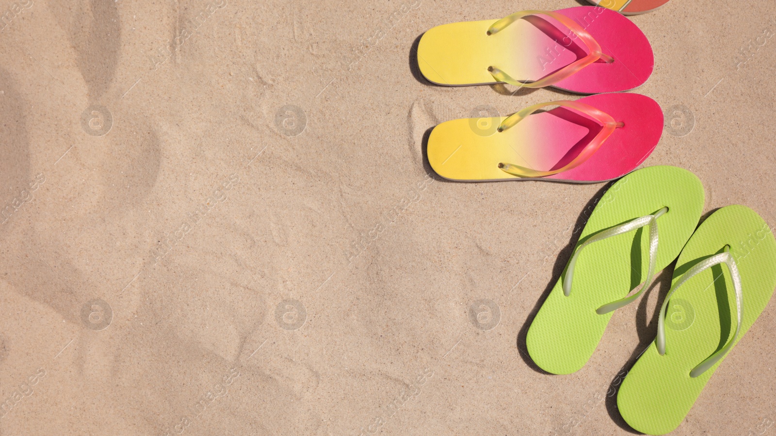 Photo of Flat lay composition with flip flops on sand, space for text. Summer beach accessories