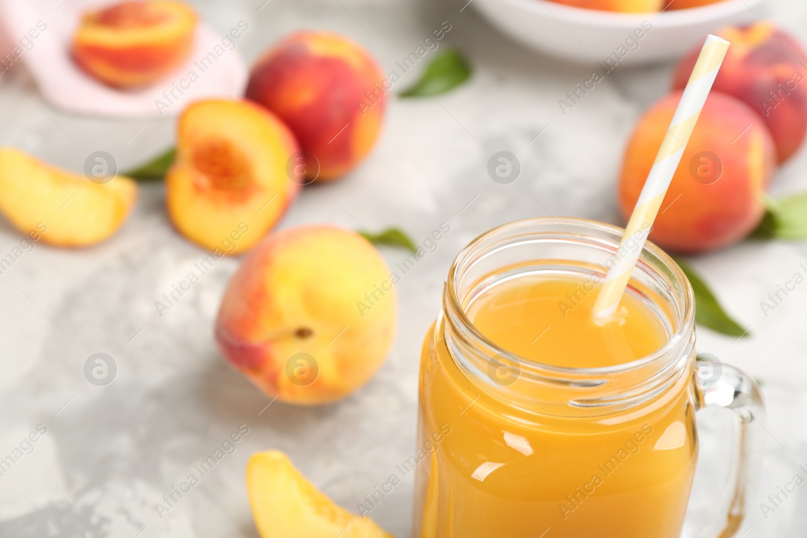 Photo of Natural peach juice and fresh fruits on grey table, closeup