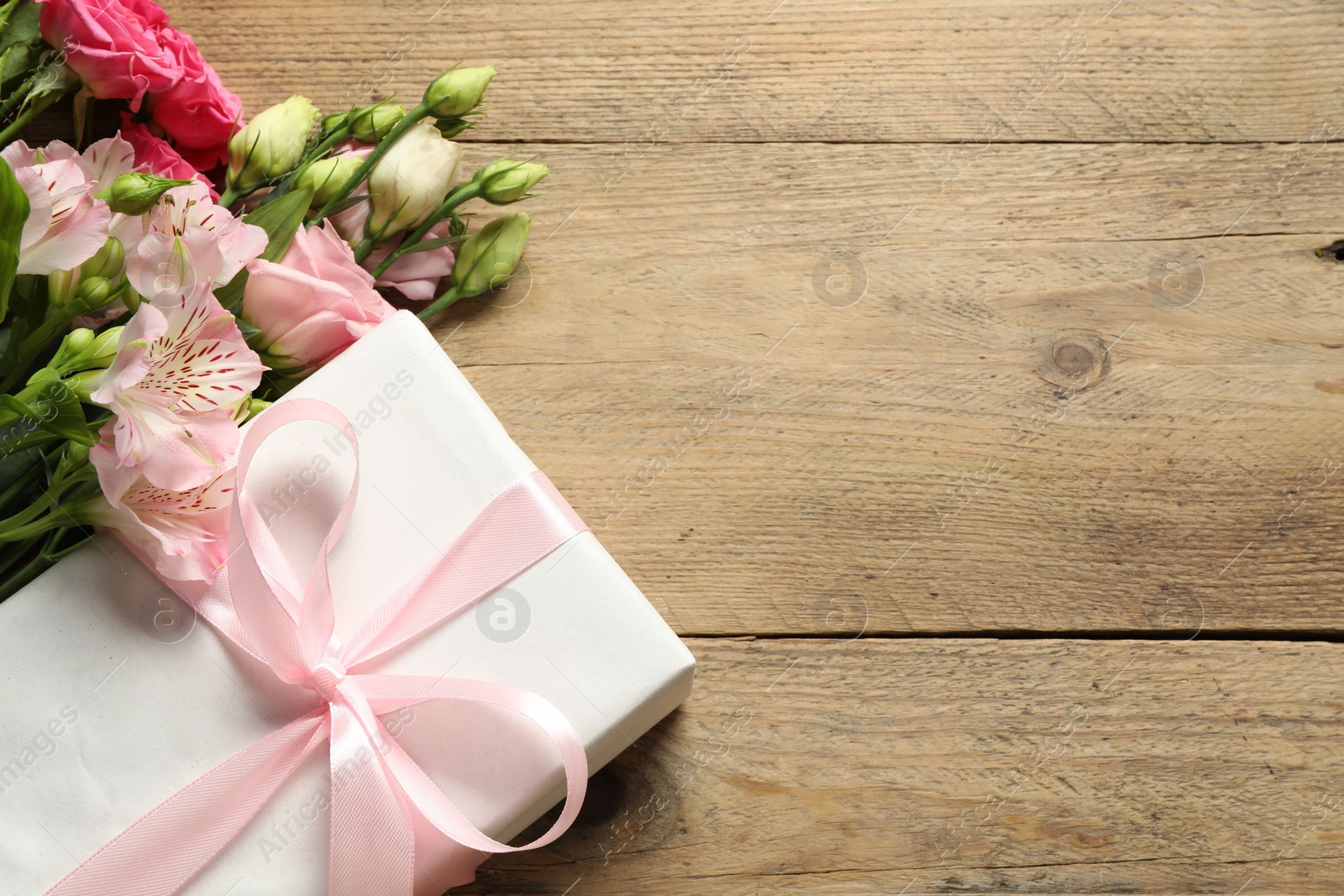 Photo of Happy Mother's Day. Beautiful flowers and gift box on wooden table, flat lay. Space for text