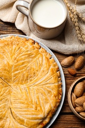 Traditional galette des rois and ingredients on wooden table, flat lay