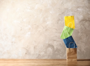 Colorful paper shopping bags on table against color background. Space for text