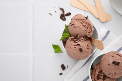 Photo of Paper cups with tasty chocolate ice cream on white tiled table, flat lay. Space for text