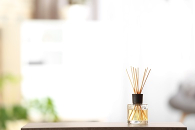 Photo of Aromatic reed air freshener on table against blurred background