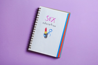 Photo of Notebook with phrase "SEX EDUCATION" on violet background, top view