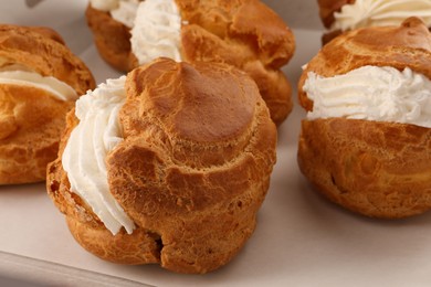 Photo of Delicious profiteroles with cream filling on table, closeup
