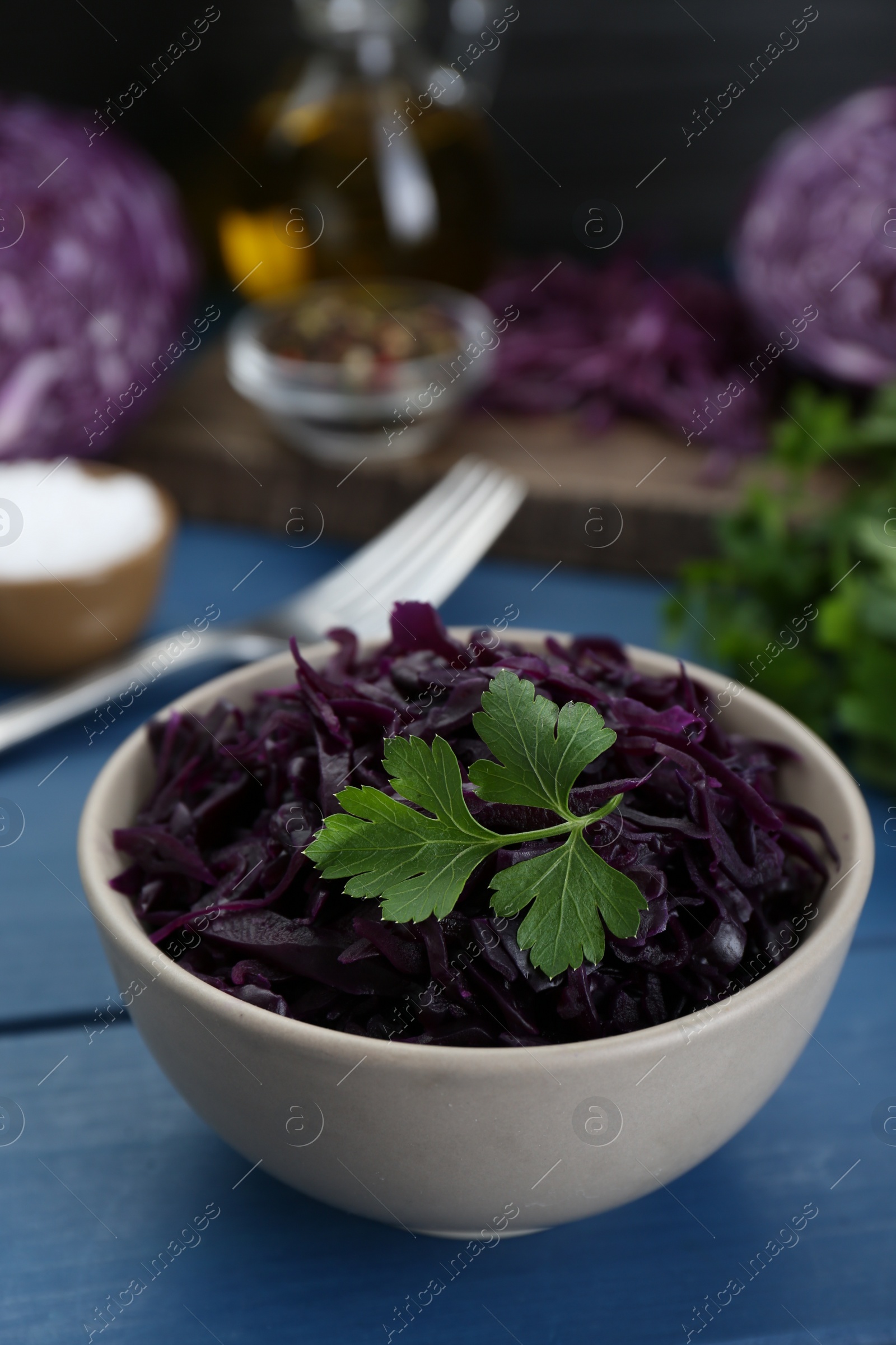 Photo of Tasty red cabbage sauerkraut with parsley on light blue wooden table