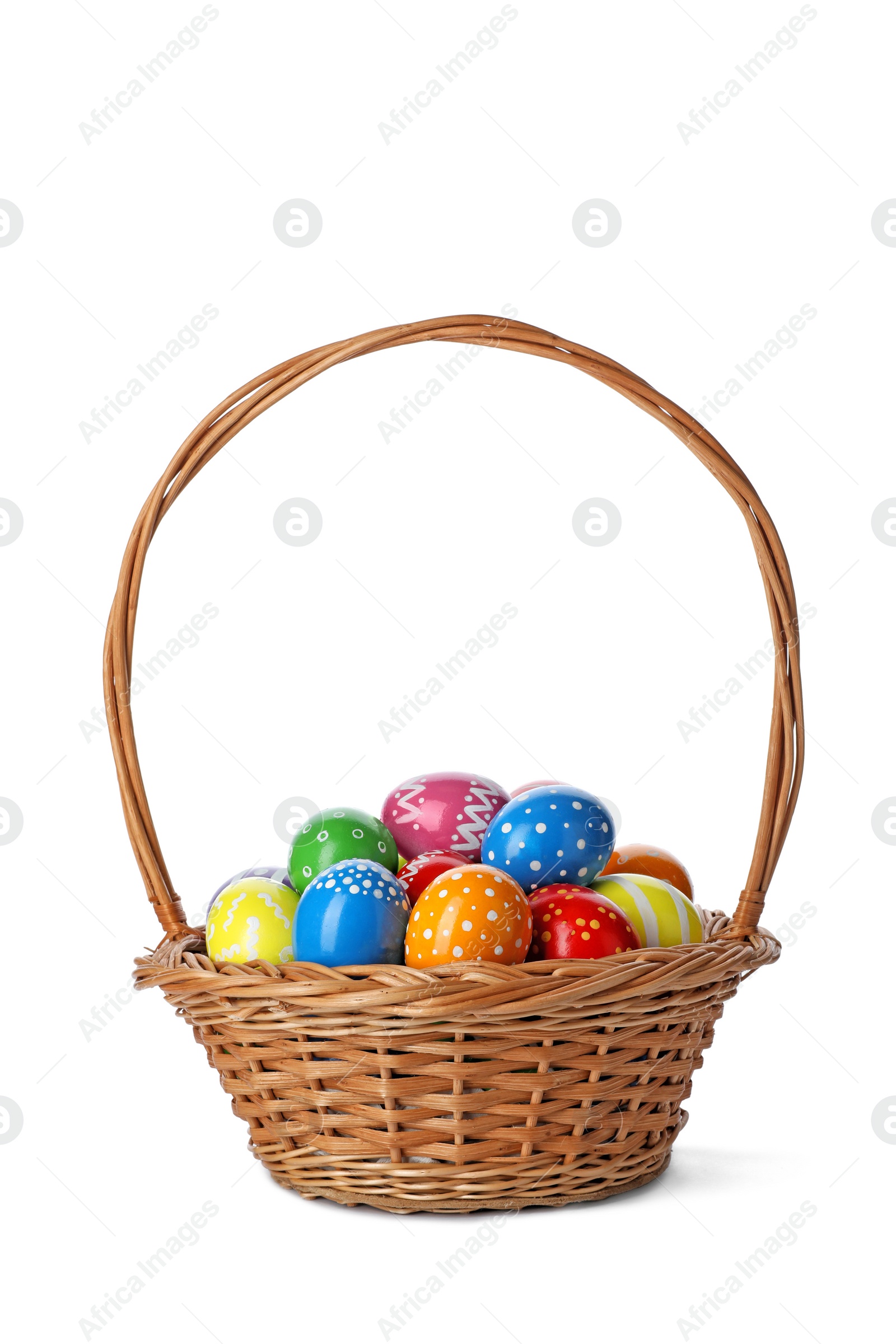 Photo of Decorated Easter eggs in wicker basket on white background