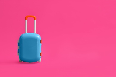Stylish blue child suitcase on pink background, space for text