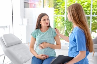 Young pregnant woman with depression and her doctor in clinic