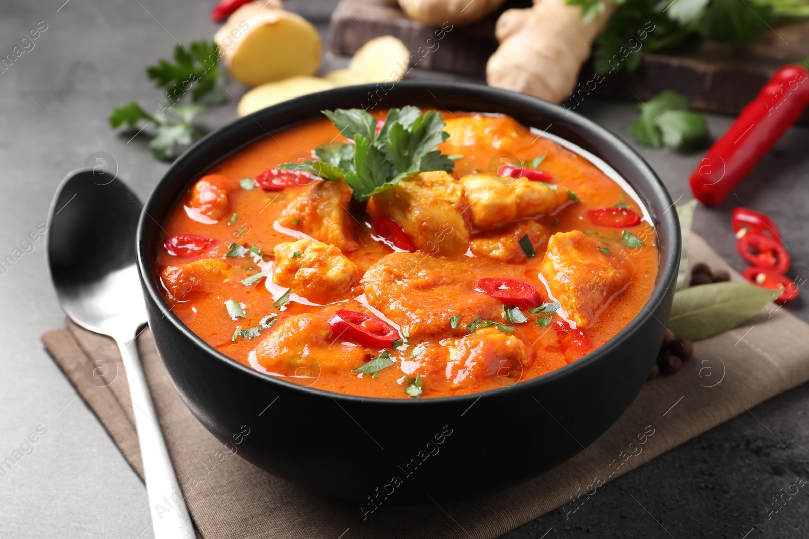 Photo of Bowl of delicious chicken curry on grey table