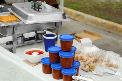 Photo of Volunteer food distribution. Different tasty meals served on table outdoors