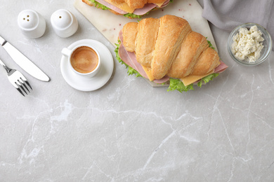 Photo of Tasty croissant sandwich with ham served on grey table, flat lay. Space for text