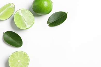 Fresh ripe limes and leaves on white background, flat lay. Space for text