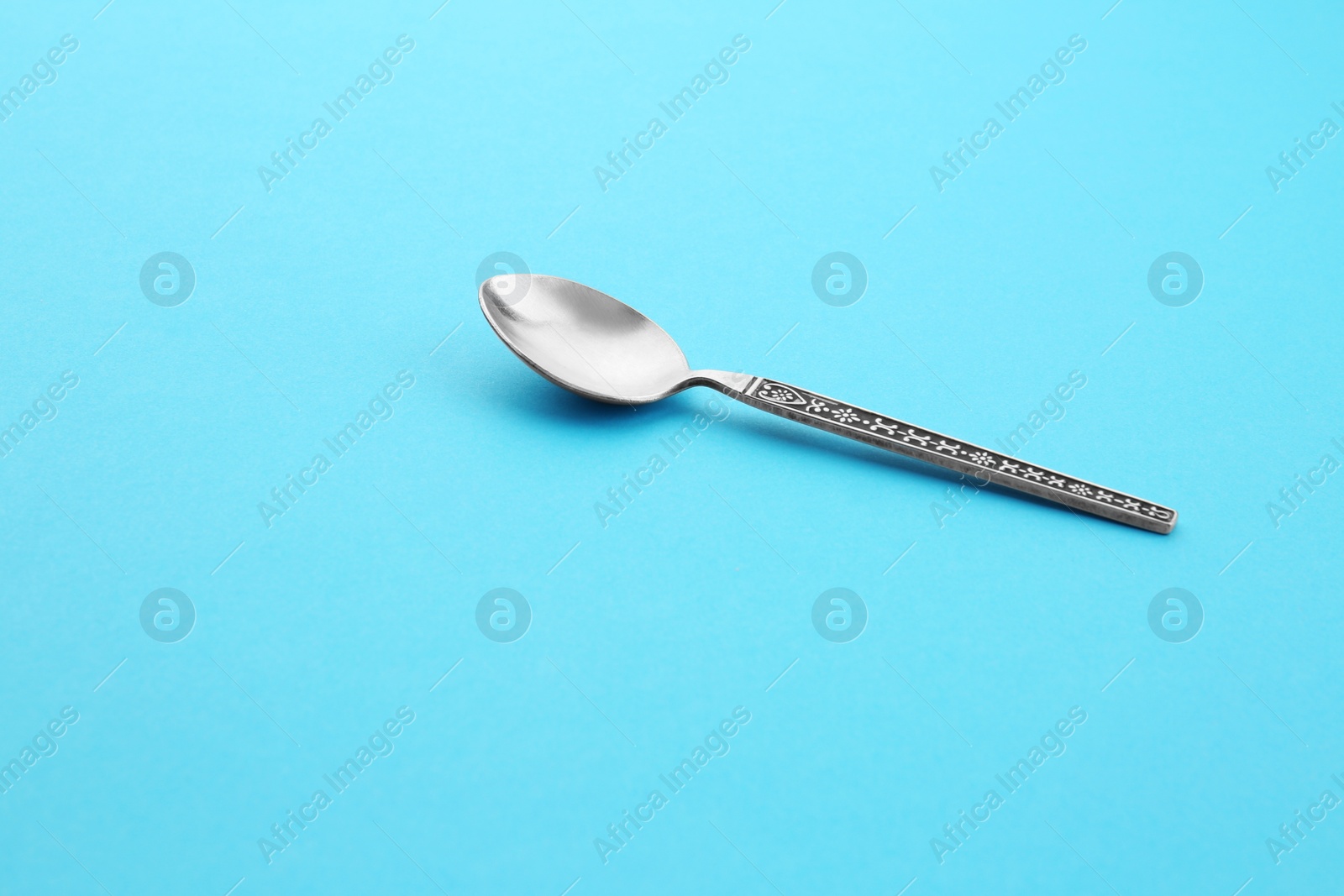 Photo of Clean empty vintage tea spoon on blue background, space for text