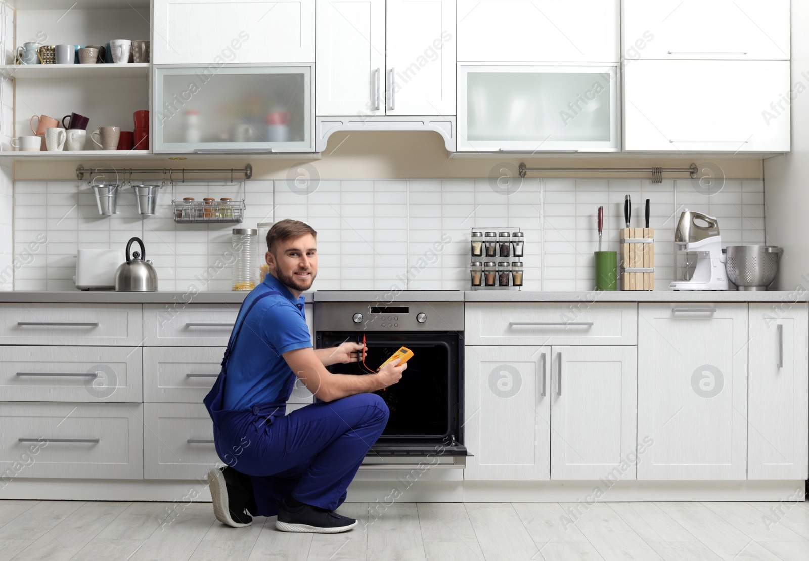 Photo of Professional serviceman repairing modern oven in kitchen