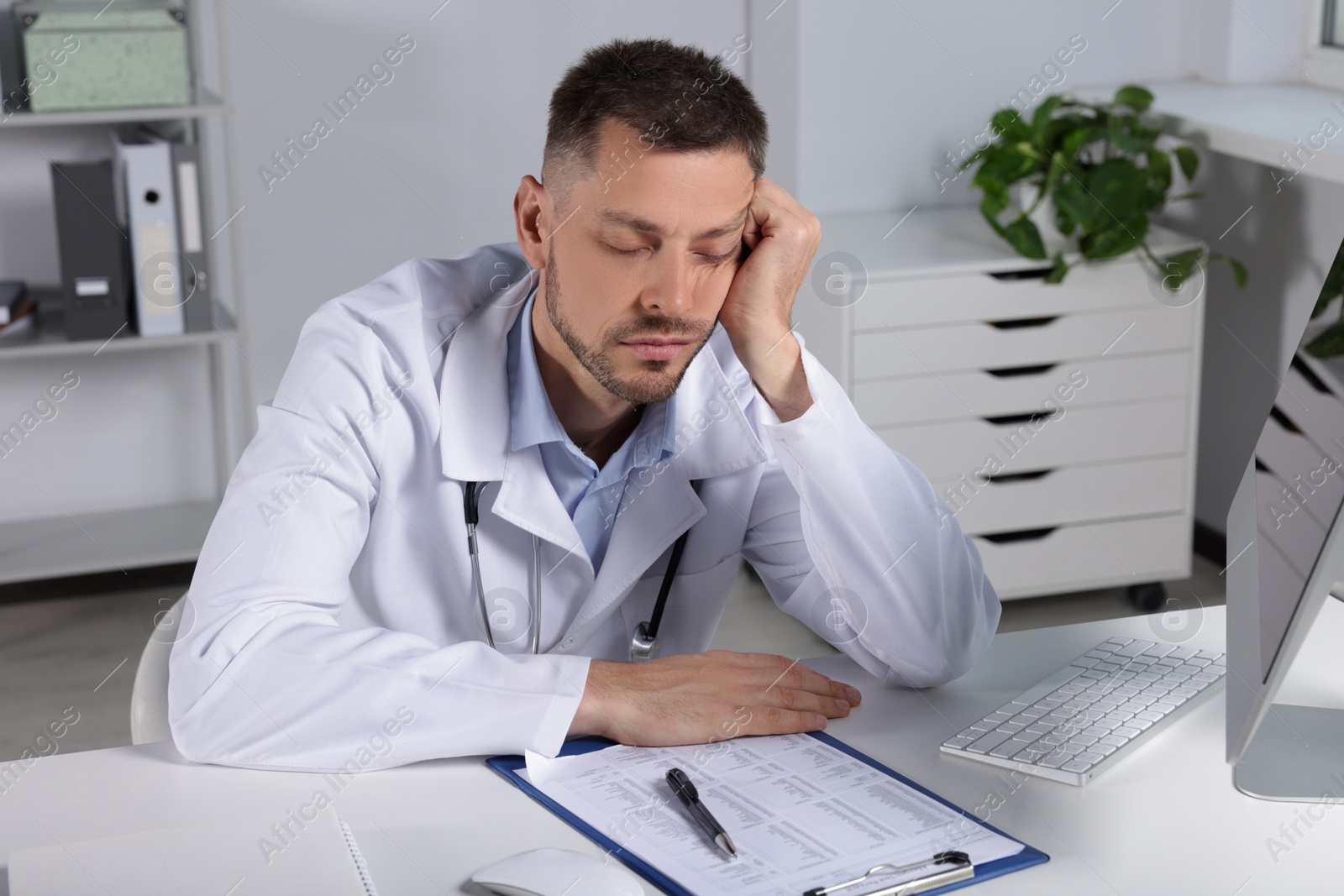 Photo of Exhausted doctor sleeping at workplace in hospital