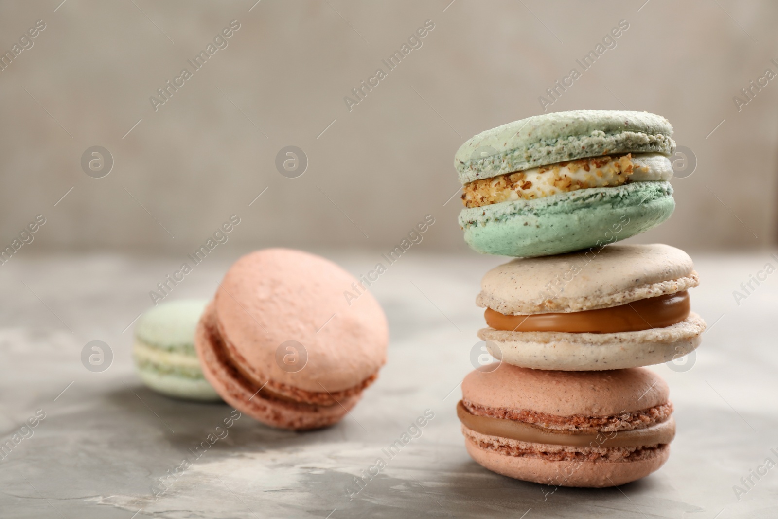 Photo of Different delicious macarons on light grey table. Space for text