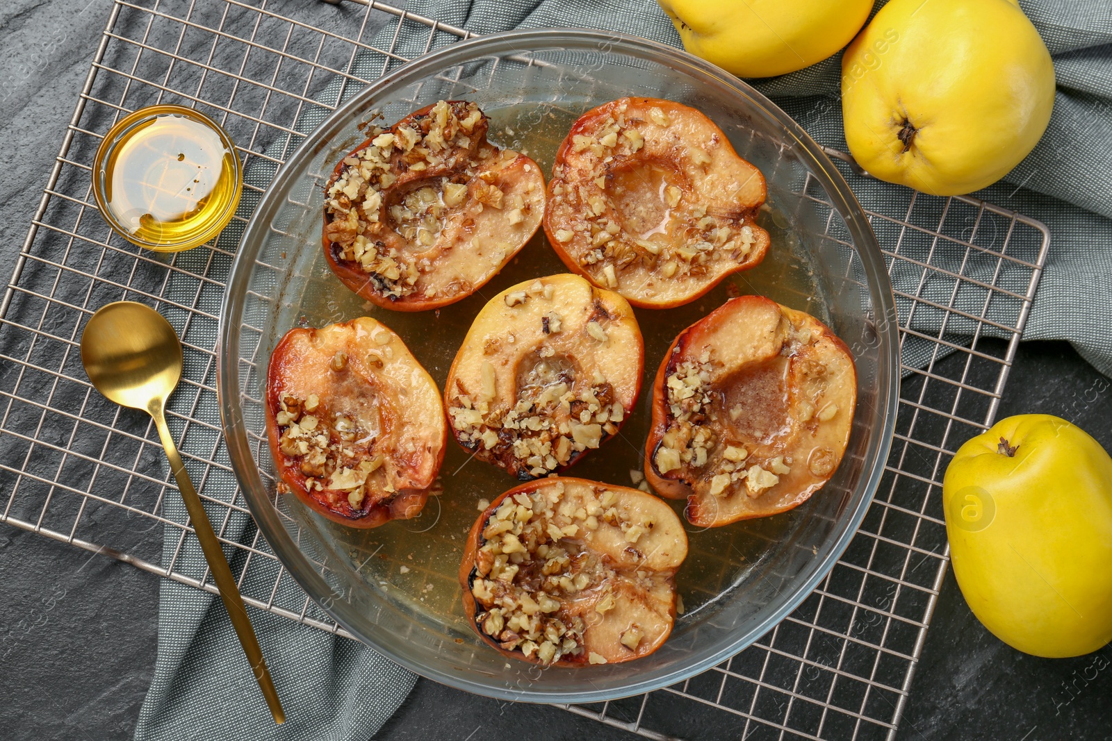 Photo of Tasty baked quinces with walnuts and honey in bowl on black table, flat lay