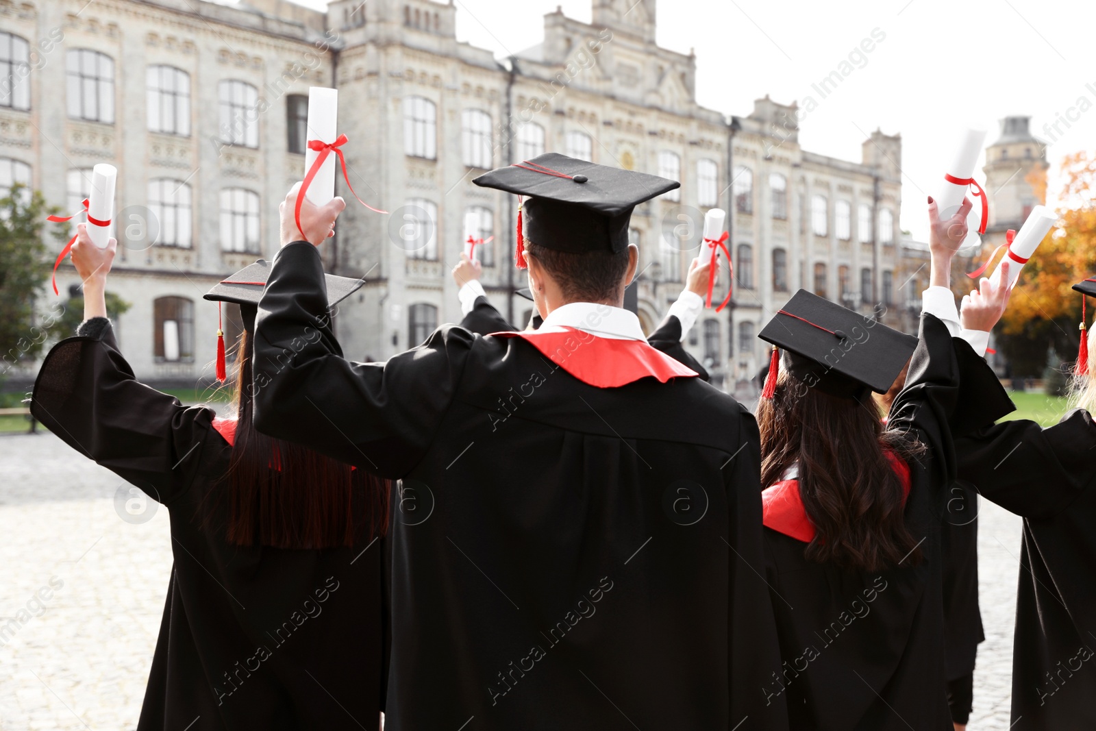 Photo of Group of students with diplomas outdoors. Graduation ceremony