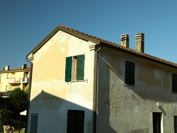 Old building with wooden shutters on sunny day