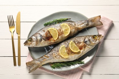 Photo of Delicious baked fish served on white wooden table, top view