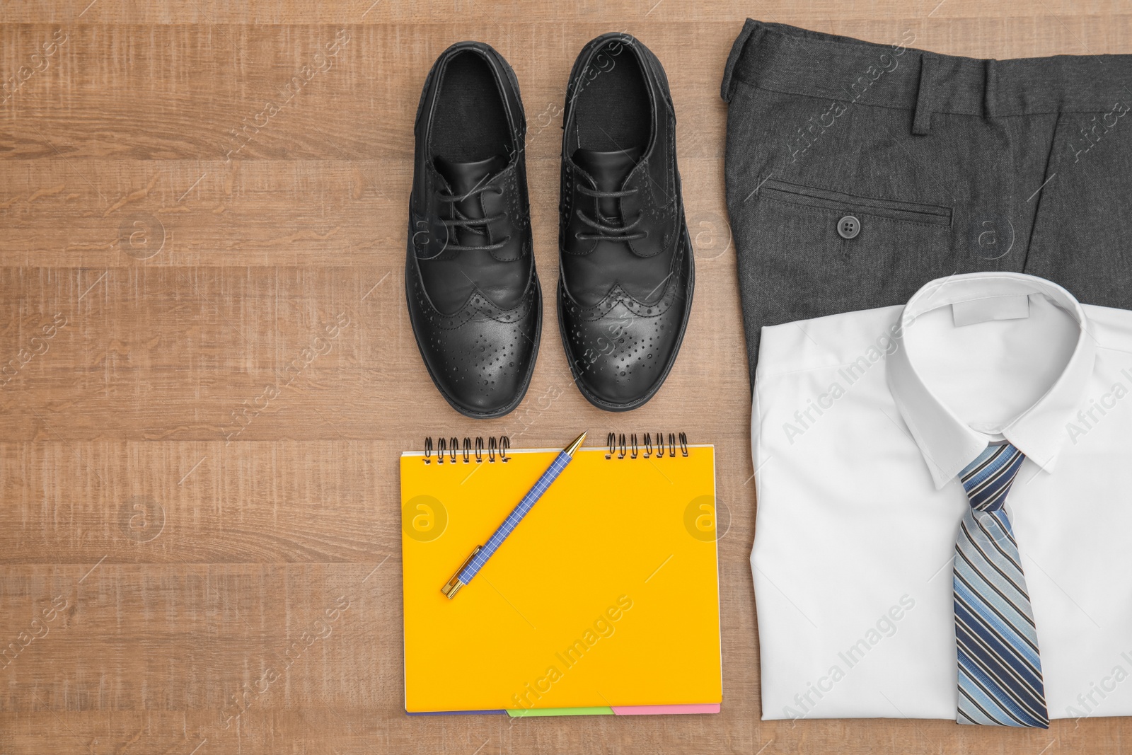 Photo of School uniform for boy and notebook on wooden background, top view