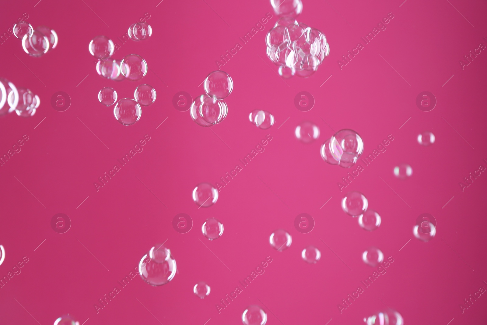 Photo of Beautiful transparent soap bubbles on pink background