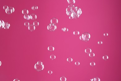 Beautiful transparent soap bubbles on pink background