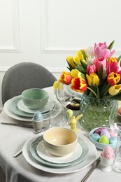 Photo of Easter celebration. Festive table setting with beautiful flowers and painted eggs