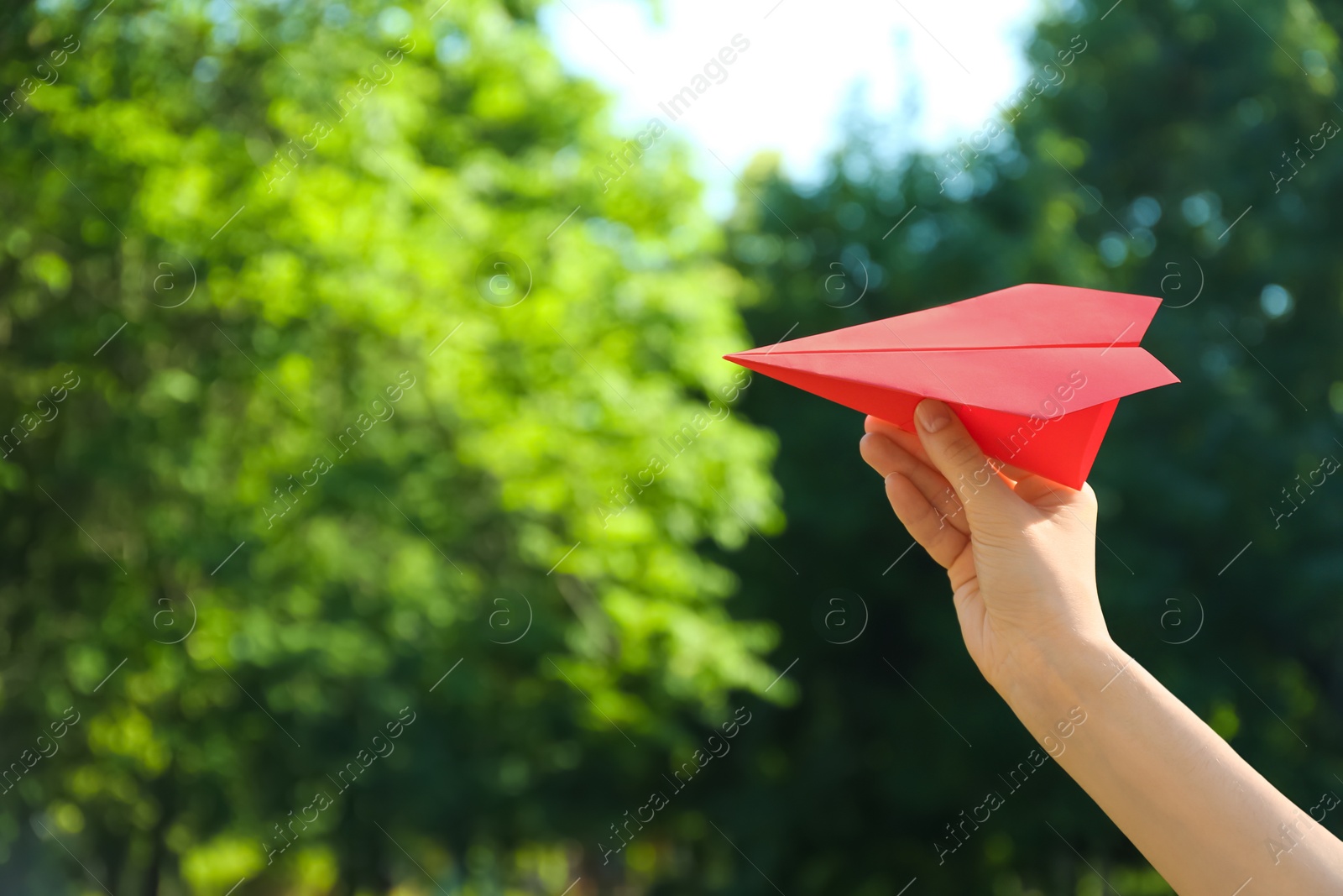 Photo of Woman holding paper plane outdoors, closeup. Space for text