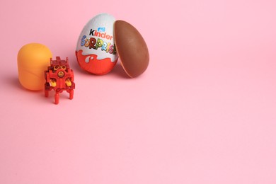 Sveti Vlas, Bulgaria - July 3, 2023: Kinder Surprise Eggs, plastic capsule and toy on pink background, space for text