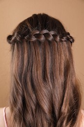 Photo of Woman with braided hair on light brown background, back view