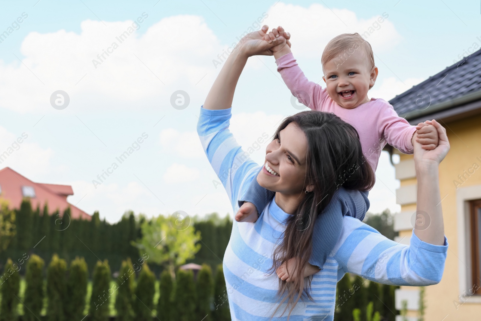 Photo of Happy mother playing with her cute baby at backyard on sunny day, space for text