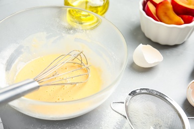 Dough and ingredients for cake on light grey table, closeup