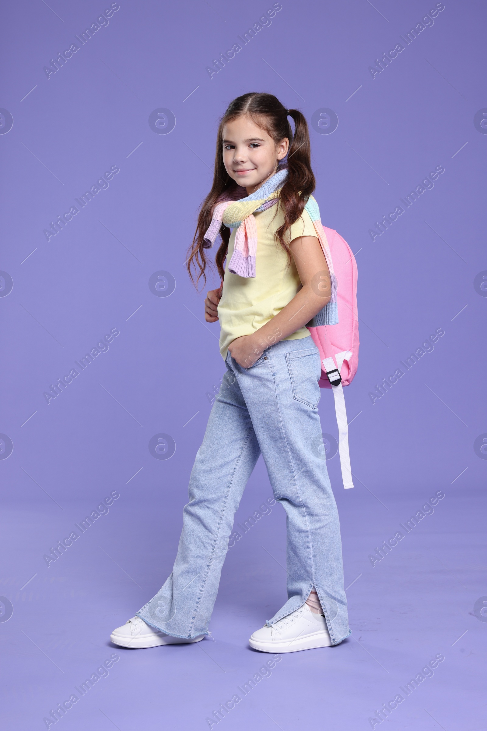 Photo of Back to school. Cute girl with backpack on violet background