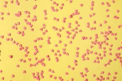 Photo of Bright heart shaped sprinkles on yellow background, flat lay