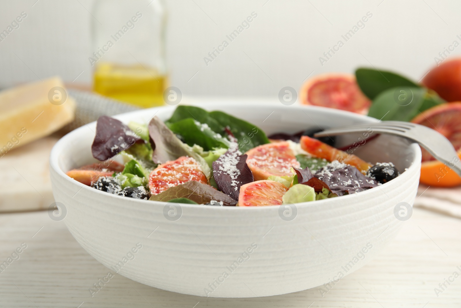 Photo of Bowl of delicious sicilian orange salad on white wooden table, closeup