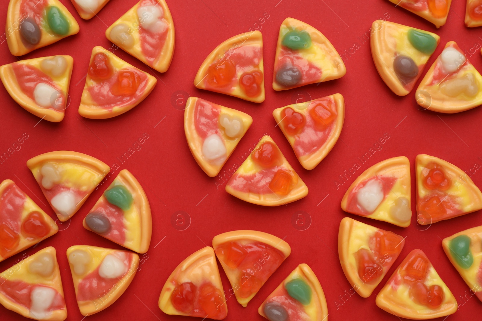 Photo of Tasty jelly candies in shape of pizza on red background, flat lay